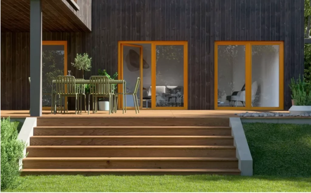 Esterno casa moderna con facciata scura, terrazza in legno, e ampie porte finestre color arancione.