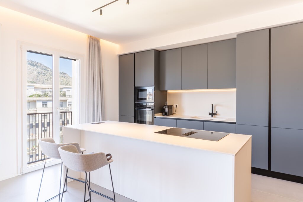 La cucina in laccato grigio è arricchita da un'elegante e pratica isola che mette in comunicazione la zona pranzo e il salotto con finestre Prolux Evolution di Oknoplast