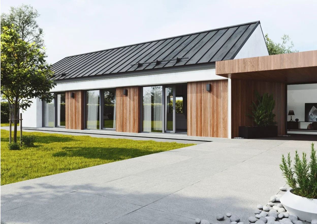 Villa moderna con tetto in lamiera scura, facciata bianca e rivestimento in legno chiaro. Ampie finestre a tutta altezza. Giardino verde e vialetto piastrellato.