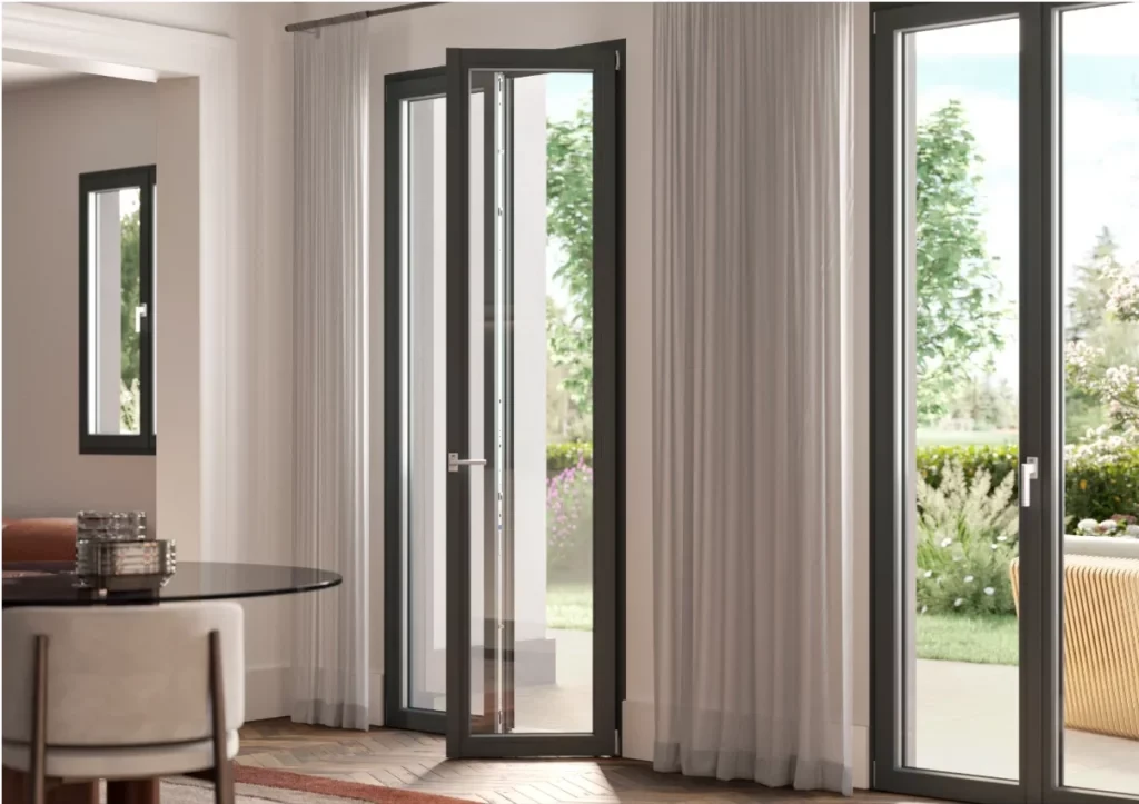 Interno moderno con grandi porte-finestre in vetro scuro che si aprono su un lussureggiante giardino verde.